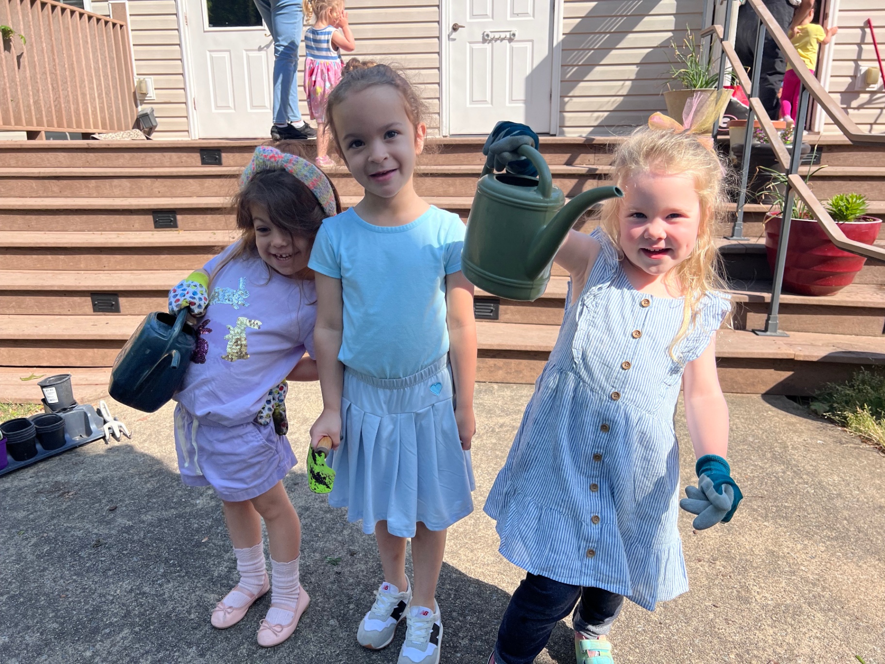 Village Montessori students with watering cans and garden gloves